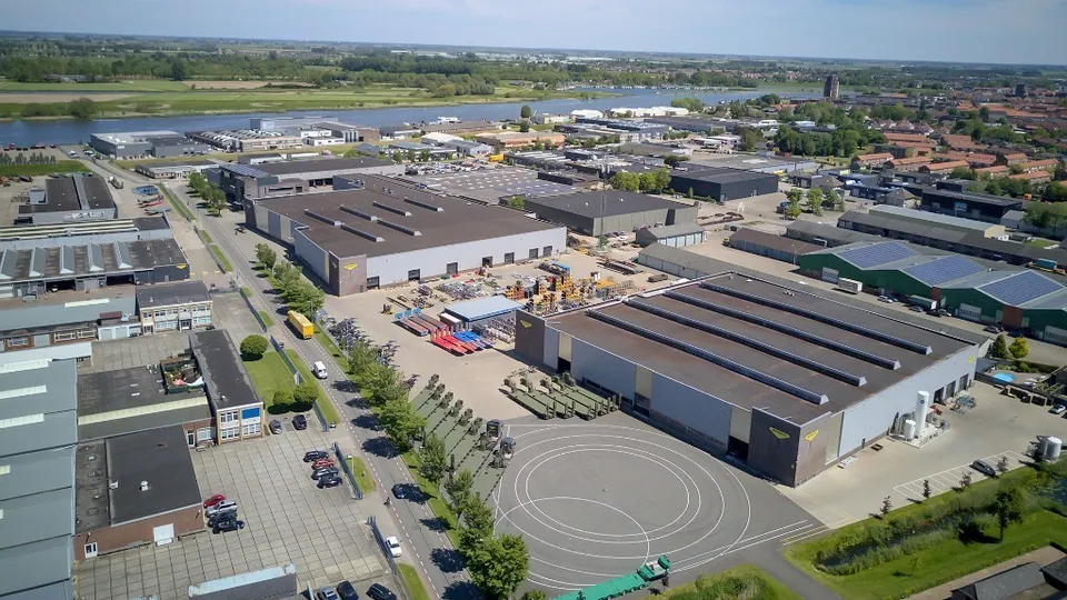 Luchtfoto van het bedrijventerrein van Broshuis met grote productiehallen langs de rivier