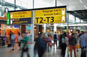 Image of inside Schiphol airport showcasing people and airport signs